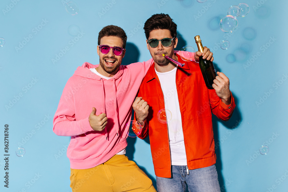 guy in orange jacket and jeans blows into party horn. Cool man