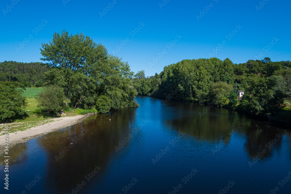 Summer landscape over River Ave in rural Portugal with blue sky and lush green trees