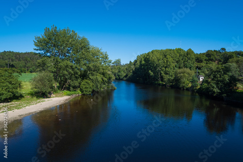 Summer landscape over River Ave in rural Portugal with blue sky and lush green trees