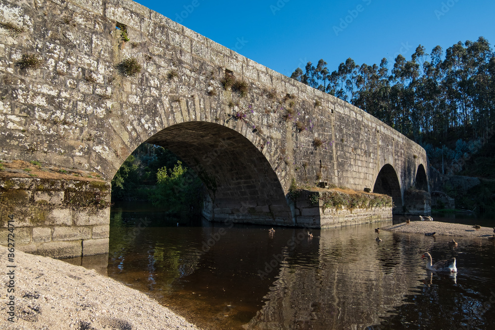 Old stone bridge over River Ave in Vila do Conde, Portugal on a sunny day in summer.