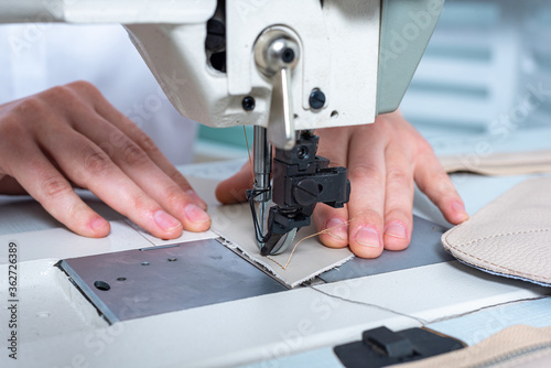 closeup female hands sew a stitch on a sewing machine