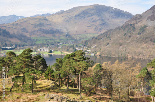 village in countryside surrounded by hills, trees and a lake photo