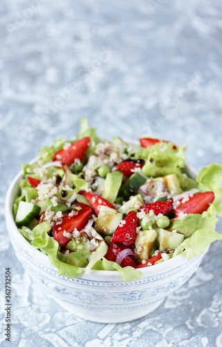 Salad with strawberries  quinoa  avocado  cucumber  lettuce  onions and green peas. vegetarian food.copy space