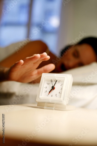 Quadro em tela Woman yawning while turning off the ringing alarm clock