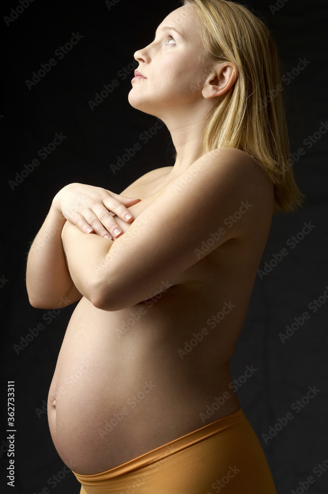 Naklejka premium Topless pregnant woman covering her breasts
