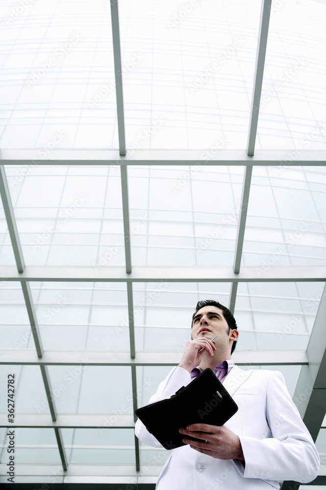 Businessman thinking while holding an organizer Businessman thinking while holding an organizer