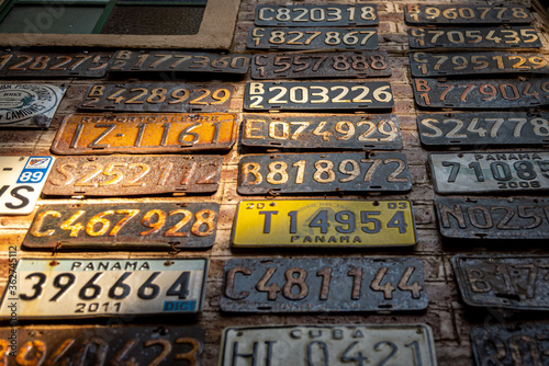 Photography Collage of old, rusty and grungy car license plates over a brick wall illuminate