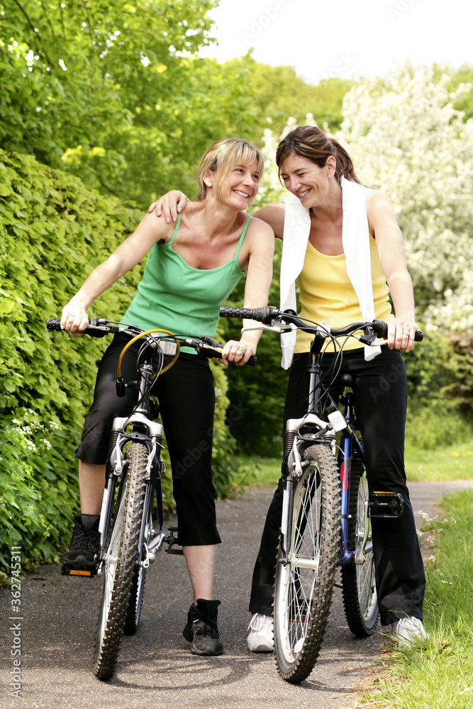 Women sitting on bicycles Women sitting on bicycles