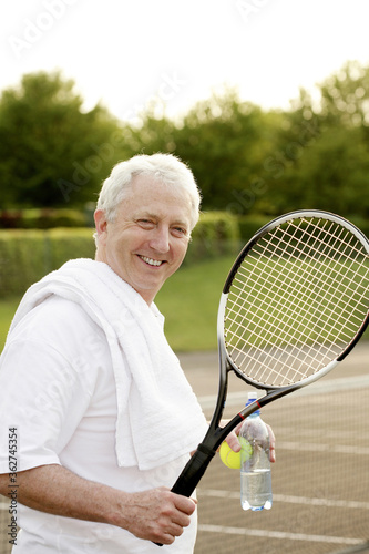 Man holding a tennis racquet and a bottle of water © ImageHit