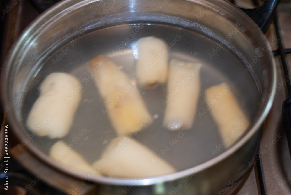cooking cassava in a pot with boiling water, Manihot esculenta. Cassava, also called mandioca, yuca, balinghoy, mogo, mandioca, kamoteng kahoy, tapioca and tapioca root. Focus selective. cooking cassava in a pot with boiling water, Manihot esculenta. Cassava, also called mandioca, yuca, balinghoy, mogo, mandioca, kamoteng kahoy, tapioca and tapioca root. Focus selective.