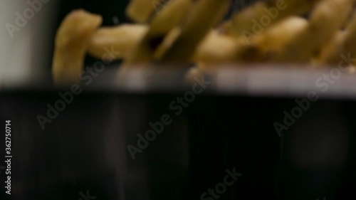 Tossing and seasoning freshly fried fries. Professional chef preparing delicious snack food. Shot in 4k. 