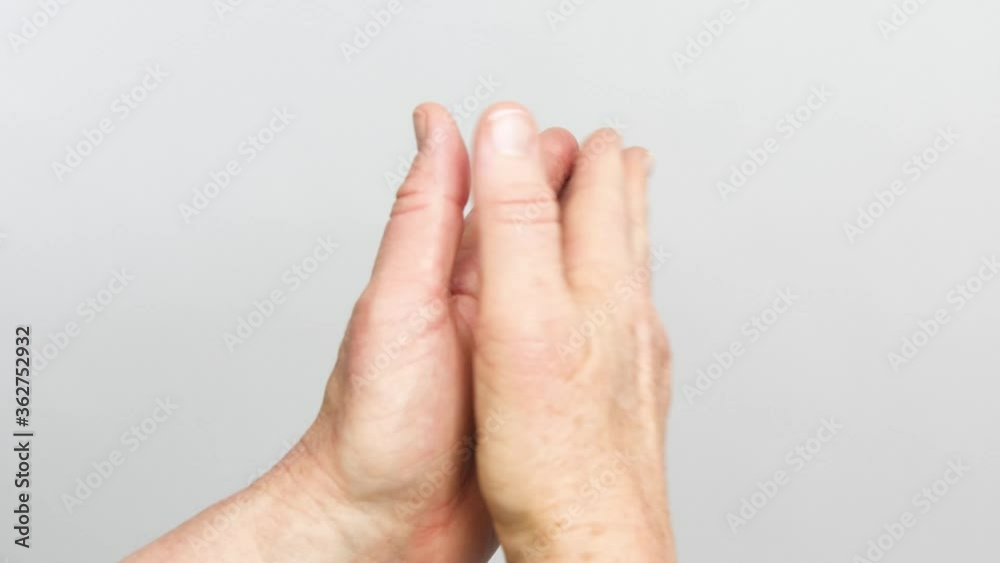 A view of hands claping from the back of the wrists is isolated on a white background. A view of hands claping from the back of the wrists is isolated on a white background.