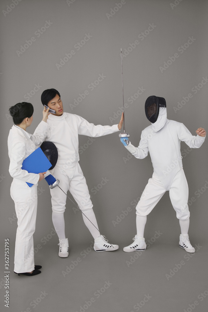 Fototapeta premium Businesswoman holding a mobile phone for a man while he stops the fencing competition