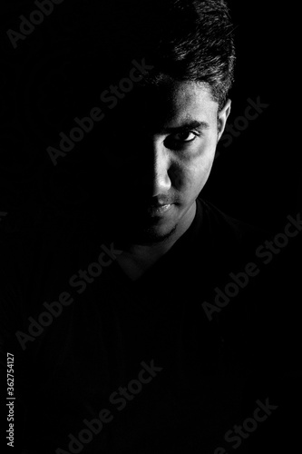Confident looking of a young man dramatic low key black and white portrait