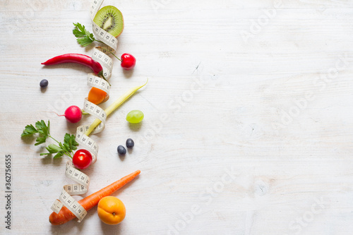 Vegetables and fruits between measuring tape on white background. Healthy diet concept