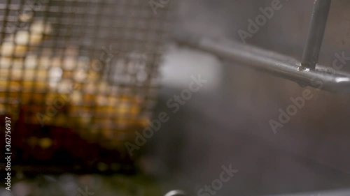 Deep frying a basket of fresh-cut french fries. Professional kitchen deep fryer. Shot in 4k  