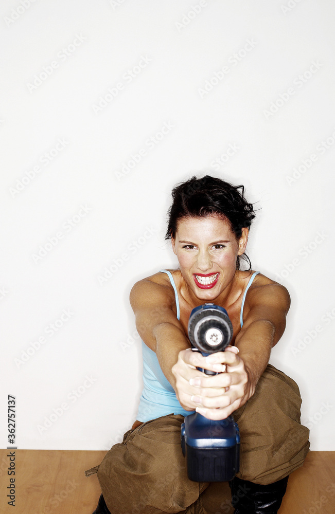 Woman pointing a drill at the camera Woman pointing a drill at the camera