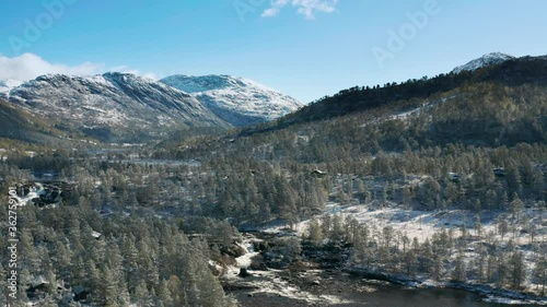 Aerial view of the vast valley of the Gaula river. The river is meandering through the valley, flowing to the waterfalls. Dense pine forest covering the valley's floor. Fresh snow is on the ground. photo