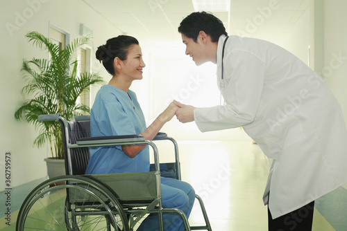 Woman on wheelchair, doctor holding her hands