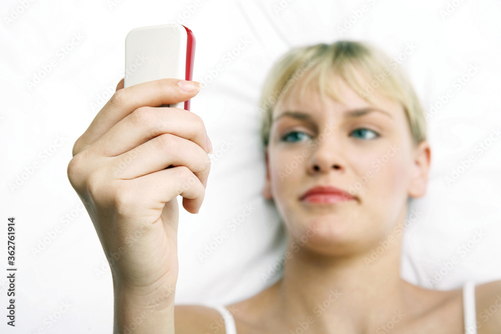 Woman text messaging while lying on the bed Woman text messaging while lying on the bed