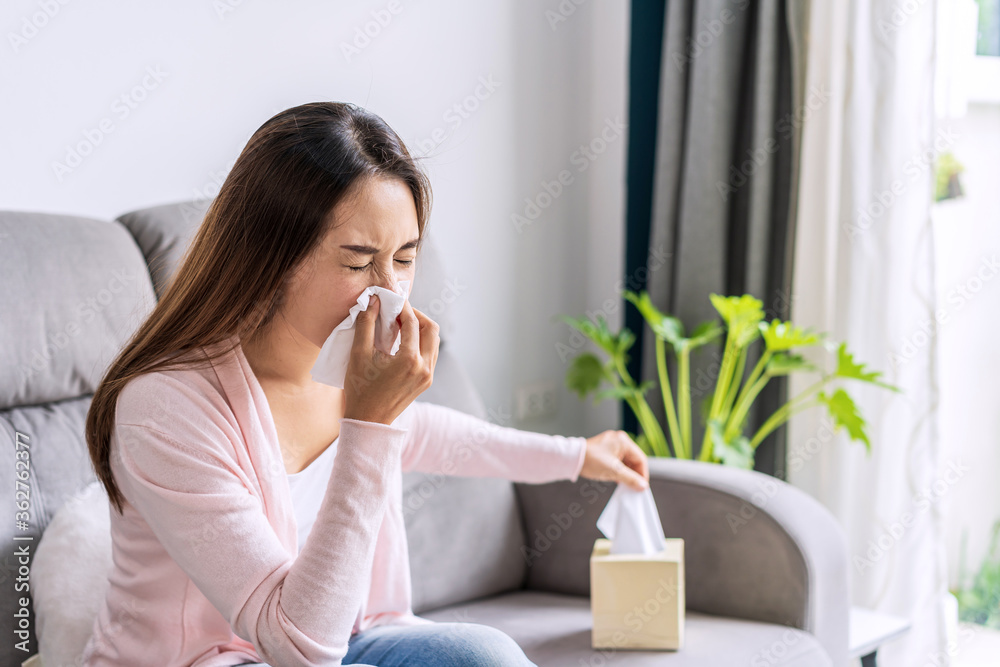Young asian women with allergies feeling unwell using tissues and sneezing at home Young asian women with allergies feeling unwell using tissues and sneezing at home
