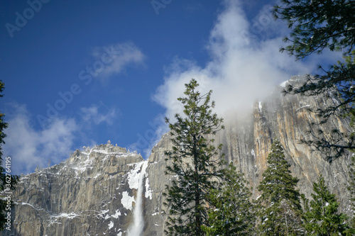 Wonderful waterfall and Half Dome at Yosemite Valley in the winter with white snow covering the trees