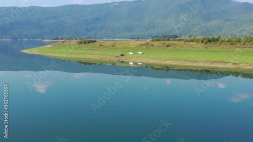 Cars parked on Rama Lake shore in Bosnia and Herzegovina with small campsite, Aerial dolly in shot photo