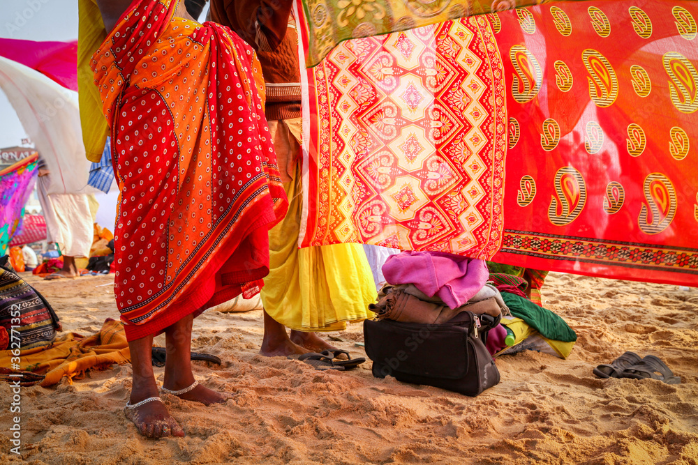 Indian women pilgrims drying their colorful sarees under sun after taking holy bath at puri beach.