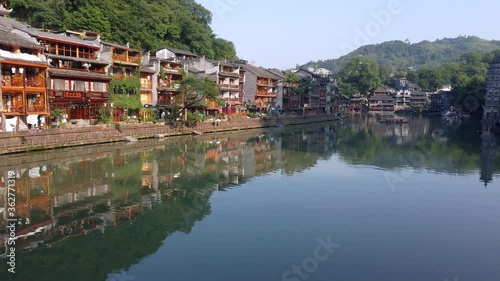 Old historic wooden Diaojiao houses on the riverbanks of Tuo river, flowing through the centre of Fenghuang Old Town photo