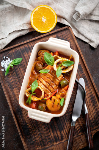 Cod stewed with vegetables and Basil in tomato sauce in a deep dish, top view photo