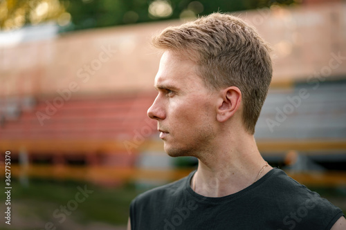 Portrait of a Young man at the stadium against the background of the sports stands, a purposeful look at the stadium