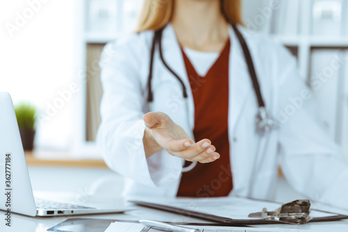 Unknown woman-doctor offering helping hand, close-up. Friendly and cheerful gesture photo