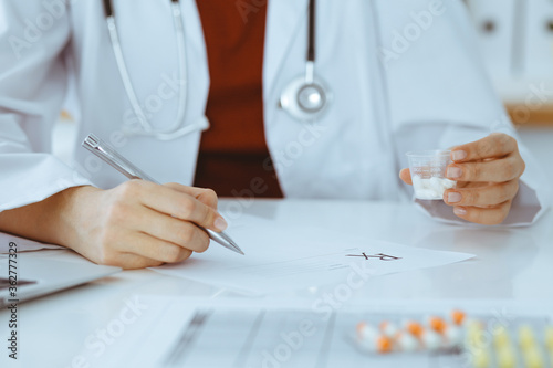 Unknown woman-doctor fills up prescription form. close-up. Panacea and life save  prescribe treatment  legal drug store. Medicine concept