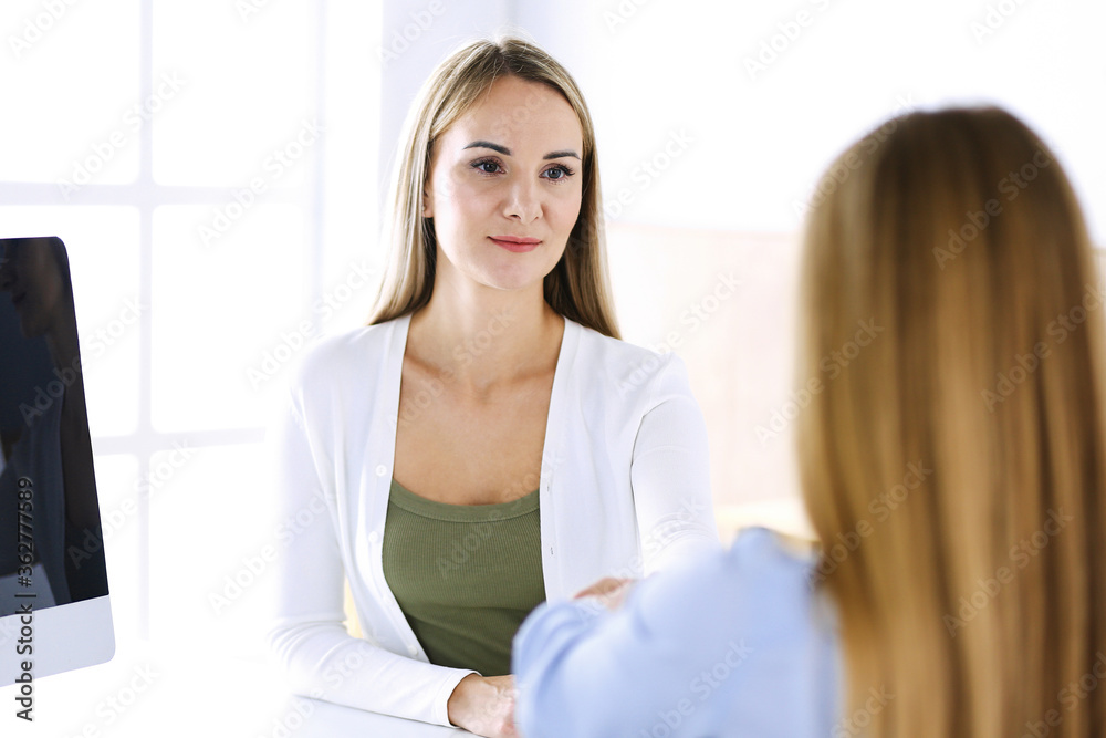 Business woman headshot while shaking hands with her female colleague or client in office. Casual white clothes style of business people. Audit, tax or lawyer concept Business woman headshot while shaking hands with her female colleague or client in office. Casual white clothes style of business people. Audit, tax or lawyer concept