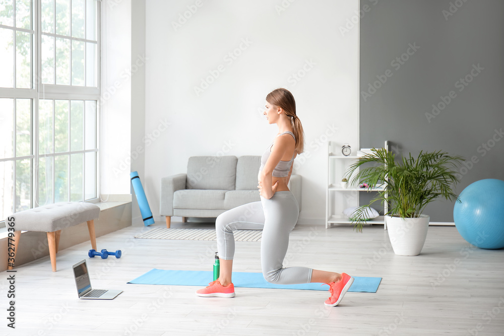 Sporty young woman with laptop training at home Sporty young woman with laptop training at home