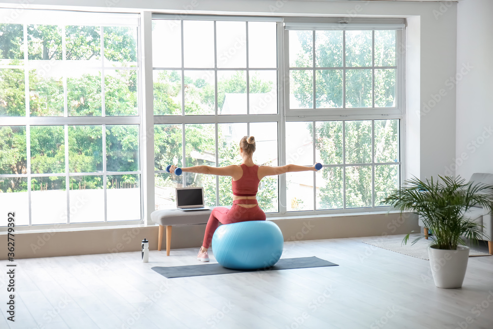 Sporty young woman with laptop training at home Sporty young woman with laptop training at home