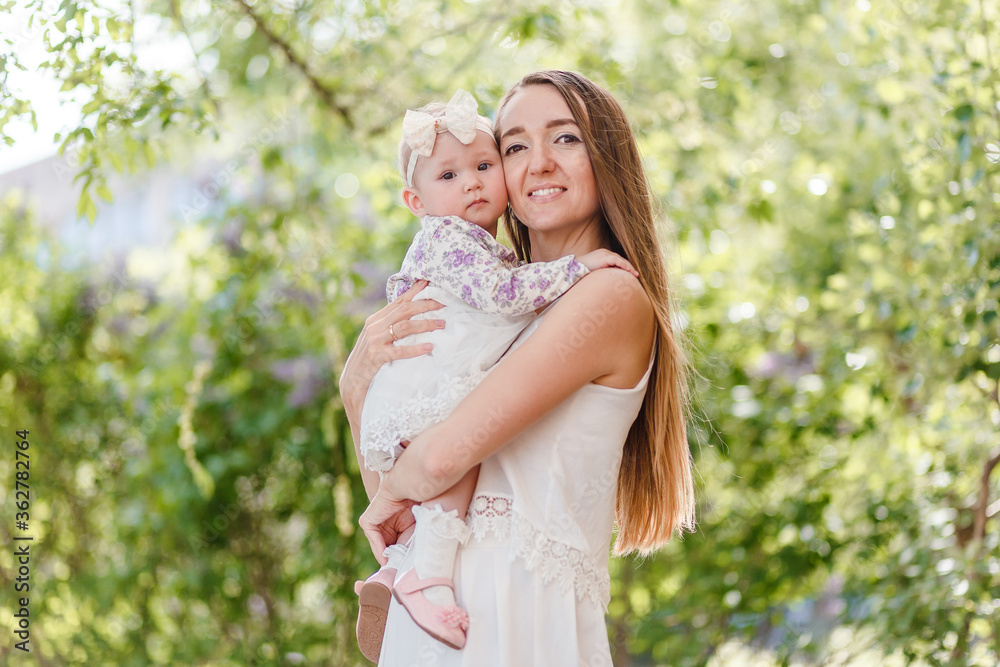 Smiling woman with long hair hugs baby summer Smiling woman with long hair hugs baby summer