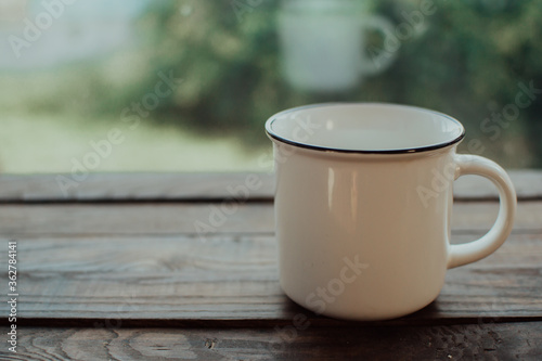 White vintage mug on the wooden table.