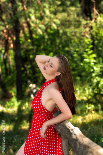 Pretty young lady in red dress walking on forest