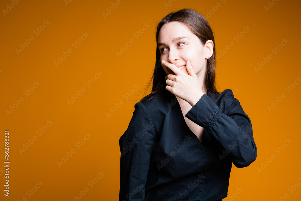 Girl on orange background shows different emotions and hands in the black shirt Girl on orange background shows different emotions and hands in the black shirt