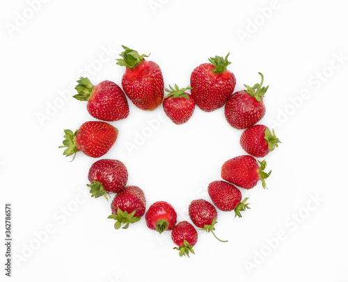 Fresh, juicy, red strawberries with green stalks in the shape of a heart on a white isolated background. The concept of wedding decoration for the cake, Valentine's Day. Holiday dessert
