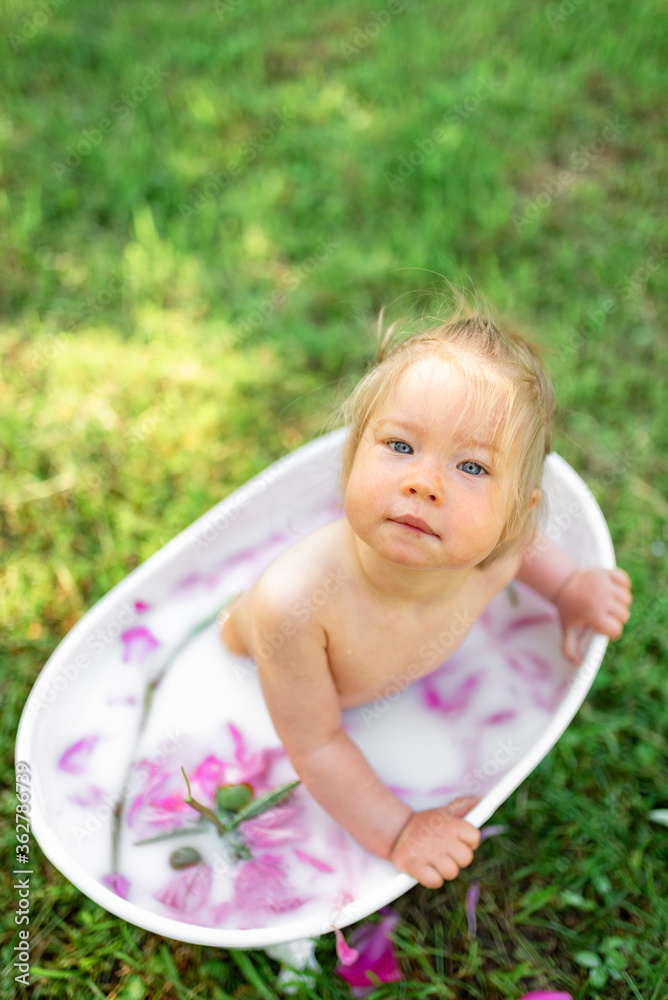 custom made wallpaper toronto digitalHappy toddler girl takes a milk bath with petals. Little girl in a milk bath on a green background. Bouquets of pink peonies. Baby bathing. Hygiene and care for young children.