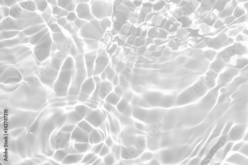 Closeup of desaturated transparent clear calm water surface texture with splashes and bubbles. Trendy abstract nature background