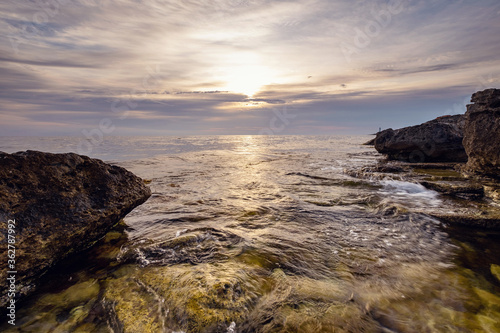 Dramatic sunset over beach with a natural pond in the foreground.