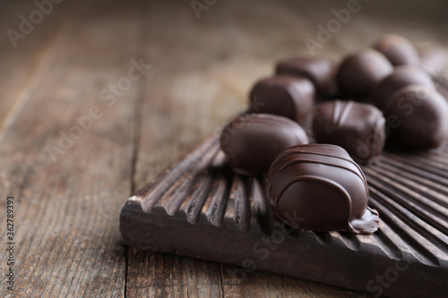 Fotografie Tasty dark chocolate candies on wooden board, closeup