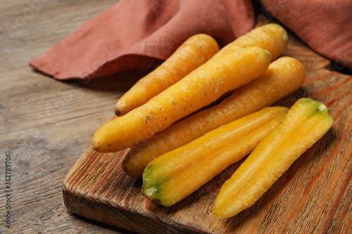 Raw yellow carrots on wooden board, closeup