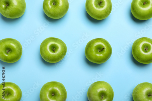 Tasty green apples on light blue background, flat lay