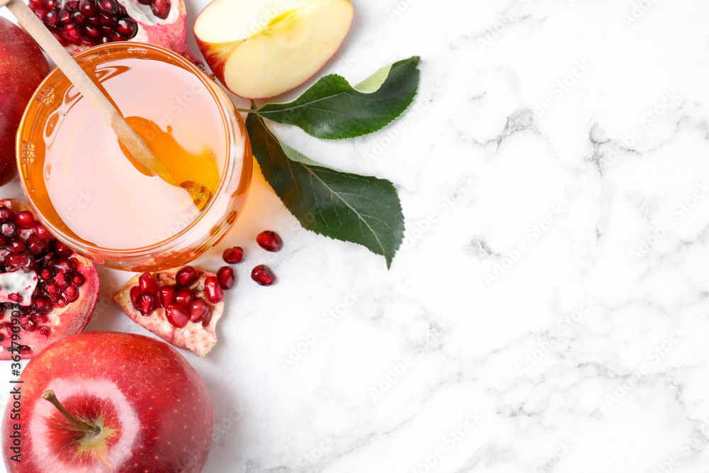 Honey, apples and pomegranate on white marble table, flat lay with space for text. Rosh Hashanah holiday Honey, apples and pomegranate on white marble table, flat lay with space for text. Rosh Hashanah holiday