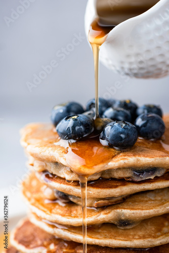 Картината върху платно Maple syrup pouring on stack of pancakes closeup view