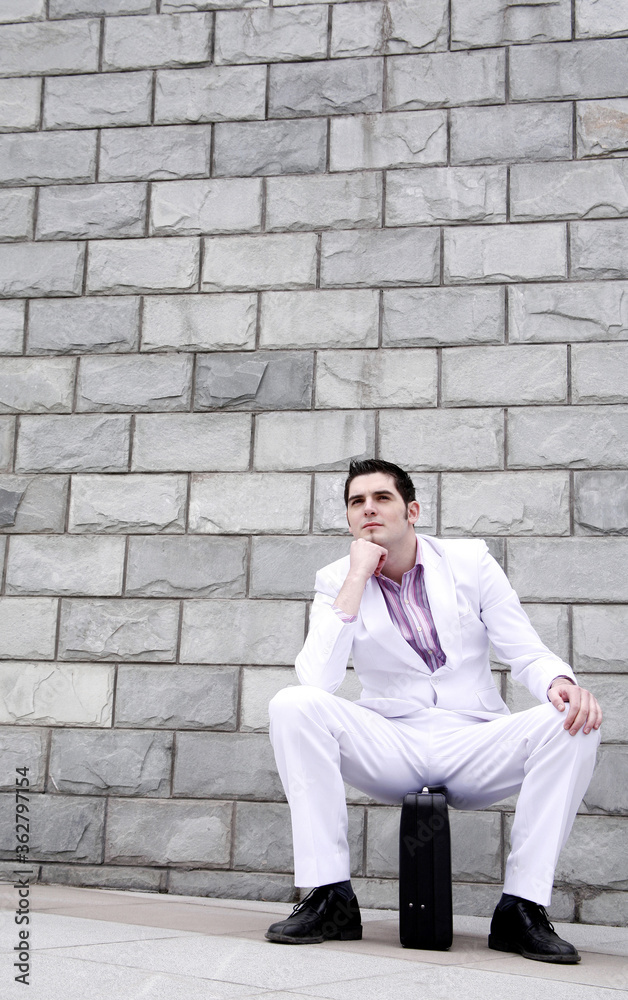 Obraz premium Businessman thinking while sitting on briefcase